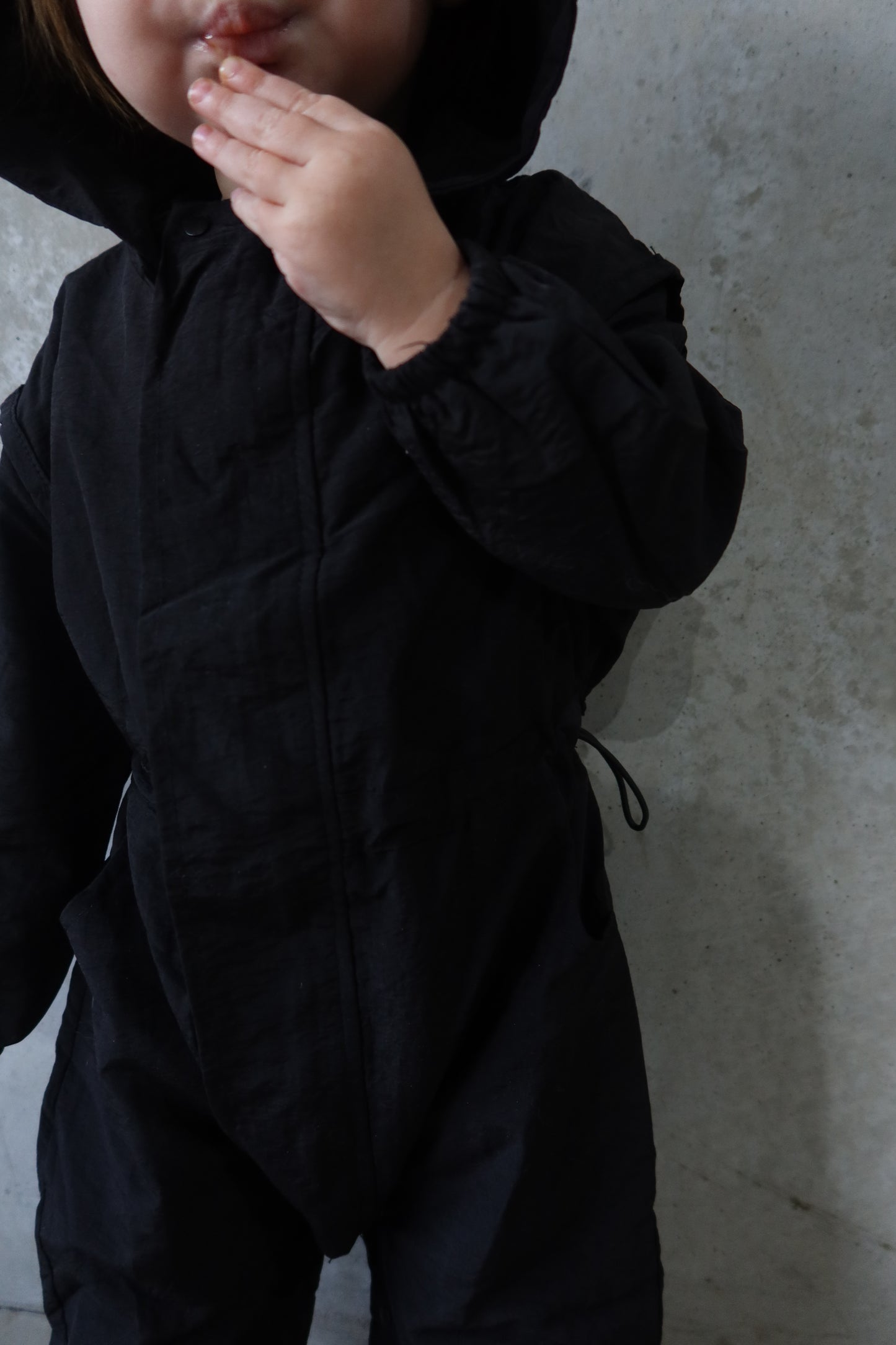 Partial close-up of the logo patch and hood toggle on Roo’s Windbreaker.
