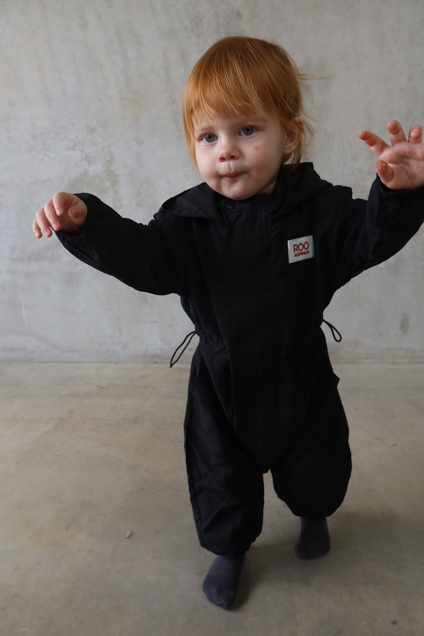 Front-facing toddler in the Windbreaker with arms wide, showing off the shape and movement of the suit.